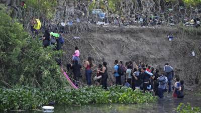 Elementos de la Guardia Nacional de Texas bloquean el paso de decenas de migrantes que cruzaron el Río Bravo este miércoles.