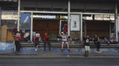 Migrantes permanecen en una estación de transporte público fuera de servicio en Tegucigalpa (Honduras). EFE/Gustavo Amador