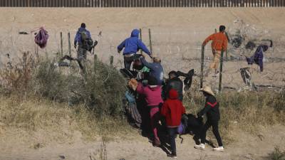 Un grupo de migrantes cruza la valla de alambres instalada en la frontera de Texas.