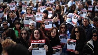Un grupo de personas muestran imágenes de los rehenes israelís durante una vigilia en Londres.