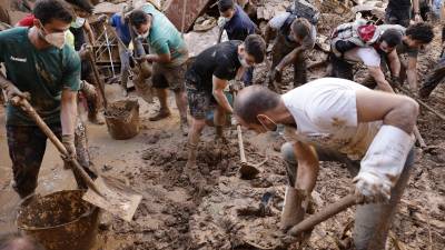 Varias personas retiran el lodo acumulado en una calle de la localidad valenciana de Paiporta, este sábado.