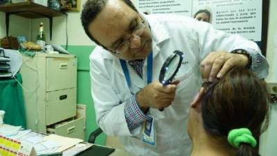 El doctor Cándido Mejía atiende a una paciente con psoriasis.