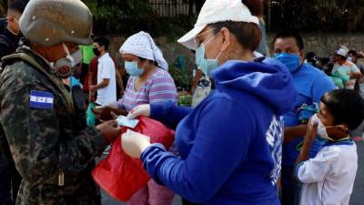 Un policía revisa documentos de ciudadanos durante una procesión este Viernes Santo en los mercados de Comayagüela de Tegucigalpa. EFE