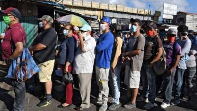 Hondureños hacen fila en mercados de Tegucigalpa para comprar víveres y así sobrellevar la cuarentena en sus hogares. Foto: AFP