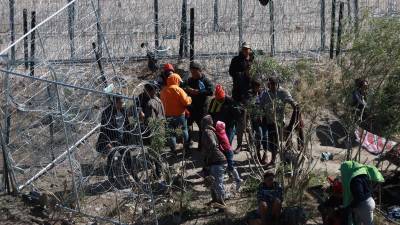 Migrantes tratan de moverse entre las mallas y alambres de púa en las inmediaciones del Río Bravo en Ciudad Juárez, Chihuahua (México).