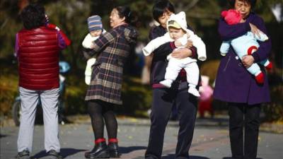Varias mujeres sujetan en brazos a bebés en un parque de Pekín, China. EFE/Archivo