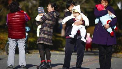 Varias mujeres sujetan en brazos a bebés en un parque de Pekín, China. EFE/Archivo