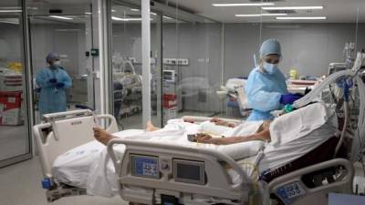 TOPSHOT - Healthcare workers attend to a patient at the Covid-19 Intermediate Care Unit (IMCU) of the Enfermera Isabel Zendal new emergency hospital, in Madrid, on January 27, 2021. - Spain has been hard-hit by the pandemic, recording more than 57,000 deaths from nearly 2.7 million cases so far. (Photo by OSCAR DEL POZO / AFP)