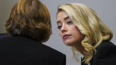 La actriz Amber Heard habla con su abogada Elaine Bredehoft durante el juicio por difamación interpuesto por su exesposo.