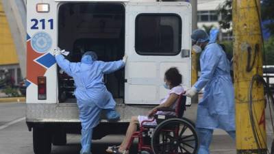 Health workers of the Permanent Contingency Commission of Honduras (COPECO) wheelchair a woman to an ambulance in Tegucigalpa on May 10, 2021 amid the COVID-19 novel coronavirus pandemic. - Honduras said Monday that El Salvador will help it buy coronavirus vaccines from China, with which Tegucigalpa does not have diplomatic ties. The announcement came a day after Salvadorean President Nayib Bukele agreed to a request from the seven opposition mayors in Honduras for vaccines for their people. (Photo by Orlando SIERRA / AFP)