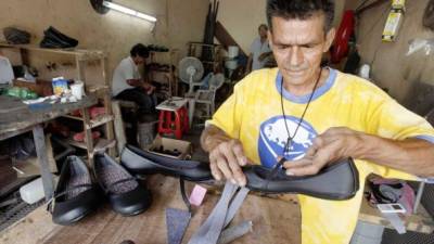 Un zapatero confecciona zapatos escolares en un puesto ubicado en un mercado sampedrano.