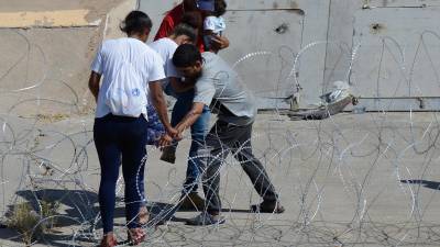 Migrantes cruzan las alambradas colocadas en el muro fronterizo para entregarse a las autoridades estadounidenses y pedir asilo, desde Ciudad Juárez, Chihuahua (México).