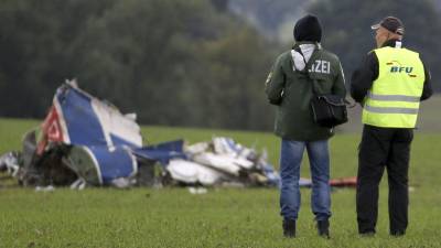 Dos hombres observan los restos de una avioneta accidentada.