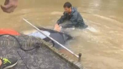 El momento en que un valiente joven logra romper el techo de un auto para salvar a una mujer de morir ahogada.