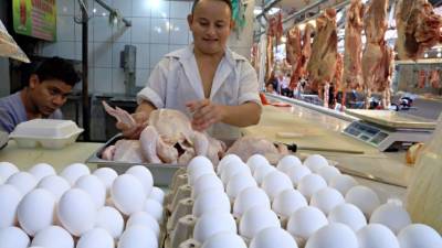 Un empleado de una carnicería del mercado Dandy corta un pedazo de cerdo. Un joven corta pollo. Foto: Cristina Santos