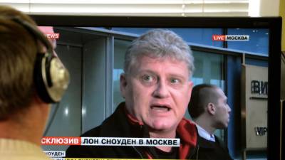 A man looks in Moscow on October 10, 2013, at a computer screen displaying Lon Snowden (R), the father of US intelligence leaker Edward Snowden, speaking during his interview with Russian website LifeNews upon his arrival in at Moscow's Sheremetyevo airport. Lon Snowden arrived early today in Moscow, hoping to meet his son for the first time since the latter became a fugitive. AFP PHOTO