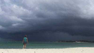 Una mujer contempla el cielo nublado mientras camina por una playa cerca de Nassau, la capital del archipiélago.