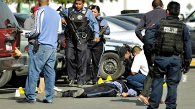 Municipal and federal police stand next to the body of a fallen officer after gunmen attacked a municipal police car in the northern border city of Ciudad Juarez, Mexico, Sunday Nov. 7, 2010. A male and a female officer were killed in the shooting. Juarez has become one of the deadliest cities in the world as rival drug gangs battle for control of smuggling routes. (AP Photo/Raymundo Ruiz)