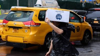 Un neoyorquino se proteje de la lluvia con una caja en la cabeza.
