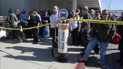 Pasajeros esperan detrás de una línea de seguridad de policía, mientras cientos son evacuados del Aeropuerto Internacional del Los Ángeles (EE.UU), después de que un desconocido abriera fuego en la terminal tres, hoy, 1 de noviembre de 2013. EFE