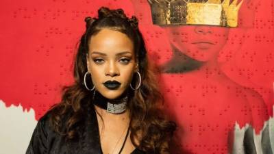 Rihanna posa con la portada de su disco.
