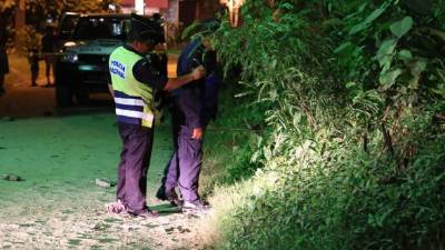 Agents of the Military POlice of Public Order (PMOP) look at a black plastic bag containing a corpse in a street in Tegucigalpa on August 19, 2020. - Corpses appeared again in the streets in an upturn of violence in northern Central America, after a truce in the beginning of the new coronavirus pandemic, when social isolation measures were taken to prevent contagions. (Photo by ORLANDO SIERRA / AFP)