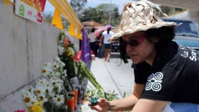 Una mujer coloca flores y enciende una vela.