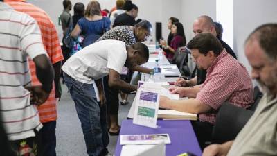 Buscadores de empleo llenan solicitudes en una feria semanal en Dallas, Texas.
