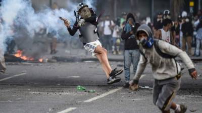 TOPSHOT - Venezuelan opposition demonstrators blocking the avenue during a protest against President Nicolas Maduro clash with riot police, in Caracas, on July 6, 2017. A political and economic crisis in the oil-producing country has spawned often violent demonstrations by protesters demanding Maduro's resignation and new elections. The unrest has left 91 people dead since April 1. / AFP PHOTO / JUAN BARRETO