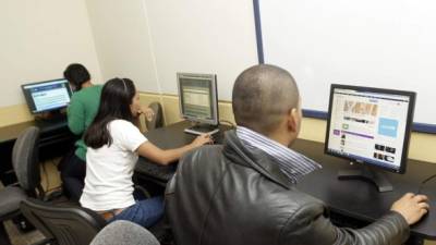 Jóvenes universitarios navegan por la red en computadoras de escritorio de un café Internet en Tegucigalpa.