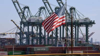 (FILES) In this file photo taken on September 29, 2018 the US flag flies over Chinese shipping containers that were unloaded at the Port of Long Beach, in Los Angeles County. - The United States is delaying until December 15 imposition of new 10 percent tariffs on Chinese electronics, but going ahead with new duties starting September 1 on $300 billion in Chinese goods, the government announced on August 13, 2019. The delay impacts cell phones, laptops, computer monitors, video game consoles and some toys, footwear and clothing, the US trade representative said in a statement. (Photo by Mark RALSTON / AFP)