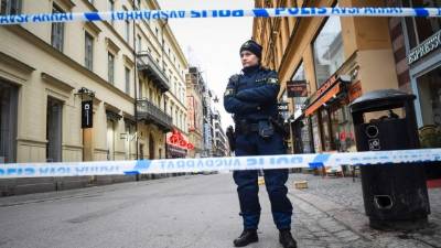 A police officer stands guard on April 8, 2017 at the site where a stolen truck was driven through a crowd and crashed into the Ahlens department store in central Stockholm the day before.The attack on Friday killed four people and injured 15, nine of them seriously. / AFP PHOTO / Jonathan NACKSTRAND