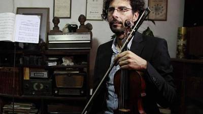 Rodolfo Escoto posa con su violín de más de 300 años de antigüedad en el salón donde ensayaba con su padre. Foto: Wendell Escoto.