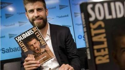 Piqué con un ejemplar del libro 'Relatos Solidarios del Deporte' que apadrina en 2014.