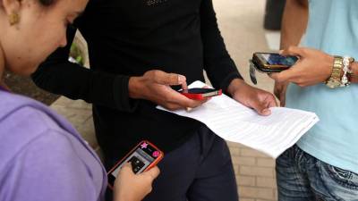 Vista de tres jóvenes que usan sus teléfonos móviles.