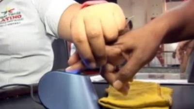 Un consumidor usa un escáner de huellas dactilares al pagar en un supermercado caraqueño.