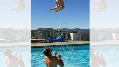 Eric Johnson, en una piscina arrojando al aire a su hijo Ace, de un año.