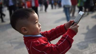 Un niño usa el iPhone 6 para tomar fotos en la Plaza de Tiananmen en Beijing. AFP