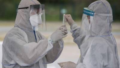 Health professionals wearing protective gear, face shield and face mask label a saliva sample at a drive-in COVID-19 testing facility in Berlin on April 30, 2020, amid the new coronavirus COVID-19 pandemic. - The testing facility, set up by the health authority of Berlin's Mitte district and operational since March 23, 2020, can administer over 150 tests a day, five days a week. (Photo by John MACDOUGALL / AFP)