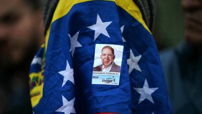 Una mujer cubierta con una bandera venezolana y una pegatina del candidato de la oposición Edmundo González Urrutia, asiste a una vigilia convocada por la oposición exigiendo la libertad de los presos políticos arrestados durante una protesta tras la impugnada reelección del presidente venezolano, Nicolás Maduro.