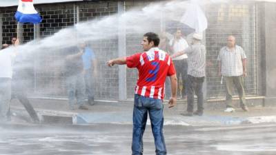 Agentes antidisturbios que acordonan el edificio, en el centro de Asunción, dispararon balines de goma a manifestantes.