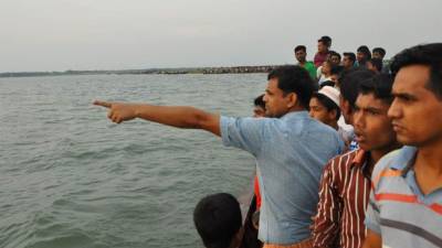 Bangladeshi residents gesture from a boat as they gather near to the site where a ferry capsized and sank in bad weather on the river Meghna in Munshiganj district, some 50 kilometres (30 miles) south of the Bangladeshi capital Dhaka on May 15, 2014. A heavily-laden ferry capsized and sank in central Bangladesh after being caught in a storm, leaving at least 10 people dead and hundreds more missing, police and officials said. Survivors of what is the latest in a string of ferry disasters to blight Bangladesh said the vessel had gone down in a matter of minutes, giving passengers little time to leap to safety. The exact number of passengers was not immediately known. It is common for ferries to carry many more than their official limit. 'We are receiving confusing figures on how many passengers were on board when it sank, but the number could range from 200 to 350,' district government administrator Saiful Hasan told AFP. AFP PHOTO/STR