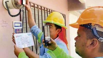 Dos empleados del programa revisan medidores de energía en el Distrito Central.