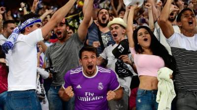 TOPSHOT - Real Madrid football team fans celebrate their team's second goal on the stands of the Santiago Bernabeu stadium in Madrid on June 3, 2017 during the UEFA Champions League football match final Juventus vs Real Madrid CF held at the National Stadium of Wales in Cardiff. / AFP PHOTO / PIERRE-PHILIPPE MARCOU