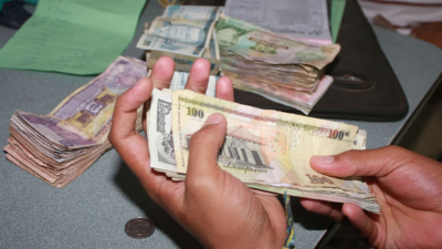 A woman holds new Bolivar-notes in downtown Caracas on August 21, 2018. - Caracas is issuing new banknotes after lopping five zeroes off the crippled bolivar, casting a pall of uncertainty over businesses and consumers across the country. (Photo by Federico PARRA / AFP)