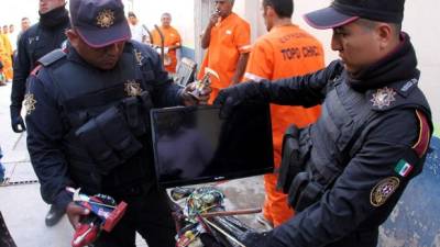 Policías muestran uno de los televisores hallados en el penal de Topo Chico.