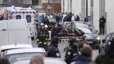 Bomberos empujan una camilla frente a la sede del periódico satírico francés Charlie Hebdo en París el 7 de enero de 2015, después de hombres armados irrumpieron en las oficinas dejando once muertos, entre ellos dos policías, según fuentes cercanas a la investigación. AFP