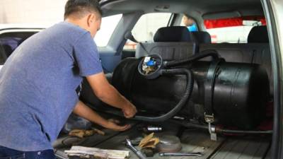 Un joven instala el sistema de gas a un taxi en el taller de Tropigas ubicado en el barrio La Guardia. Foto: Franklyn Muñoz.
