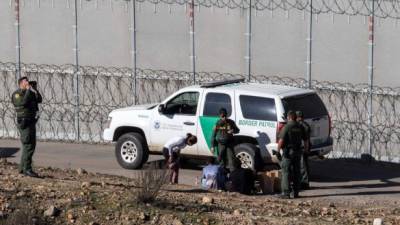 Central American migrants -traveling in a caravan- are taken into custody after crossing the Mexico-US border fence to San Diego County, as seen from Tijuana, Baja California state, Mexico on December 15, 2018. - Thousands of Central American migrants, mostly Hondurans, have trekked in a caravan for over a month in the hopes of reaching the United States. (Photo by Guillermo Arias / AFP)