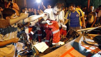 Rescatistas palestinos recogen trozos de carne en un coche alcanzado por un ataque aéreo israelí matando al conductor en la ciudad de Gaza el 9 de julio de 2014.